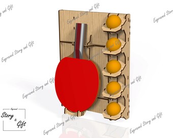 May include: A wooden wall-mounted rack for storing a ping pong paddle and balls. The rack has five slots for balls and a holder for the paddle. The paddle is red and black, and the balls are yellow.