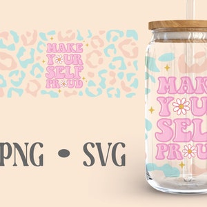 May include: A pink and blue tumbler with the text "MAKE YOUR SELF PROUD" in a retro font. The tumbler has a clear glass body and a wooden lid. There is a straw in the tumbler.
