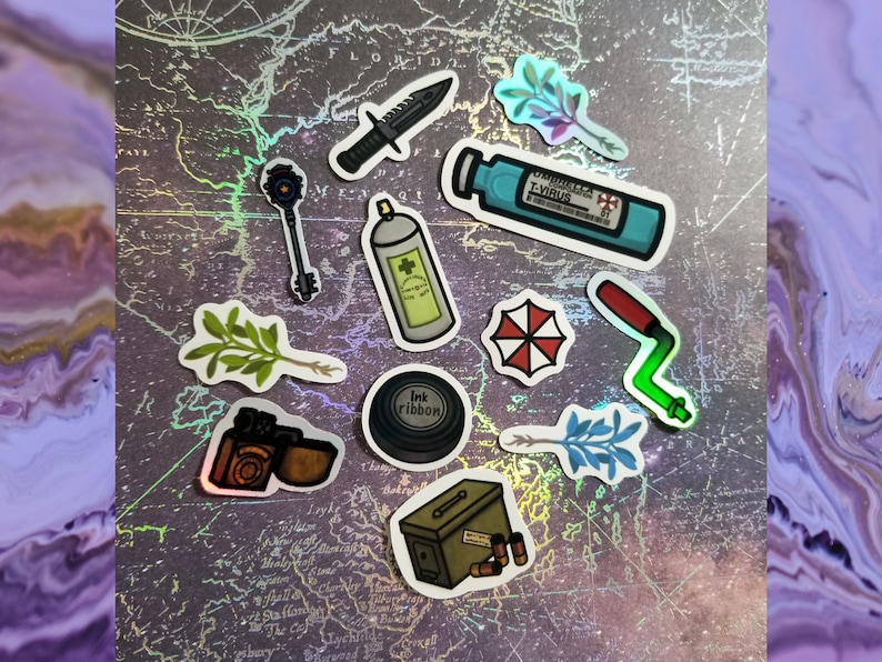 May include: A collection of stickers featuring various designs, including a knife, key, spray can, and a vial labeled "T-Virus." Other stickers depict a red and white umbrella logo, a film camera, and an ammunition box. The stickers are arranged on a map-like background.