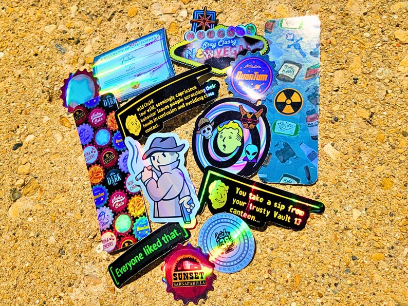 May include: A collection of colorful stickers with various designs and text. The stickers feature images of a cartoon character, a radiation symbol, and the text "Stay Classy New Vegas". Other stickers have the text "Everyone liked that."