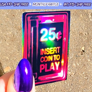 May include: A holographic sticker with a retro arcade game design. The sticker is black with a red, pink, and blue iridescent glow. The sticker says "25¢ Insert Coin to Play".