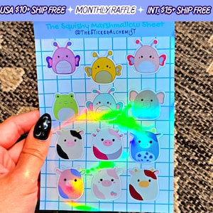 May include: A sheet of holographic stickers featuring various cute cartoon characters, including a frog, a cow, and a butterfly. The stickers are arranged in a grid pattern on a blue and white background. The text "The Squishy Marshmallow Sheet" and "@THE STICKERALCHEMIST" is printed at the top of the sheet.