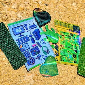 May include: A collection of colorful stickers with tech-themed designs. Includes a binary code strip, a computer parts sheet, and circuit board shapes. The stickers feature shades of green, blue, and yellow, with some holographic elements.