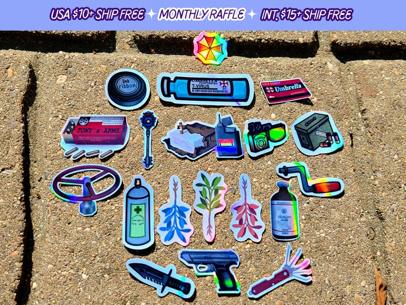 May include: A collection of holographic stickers featuring various designs. Included are stickers of an ink ribbon, a key, a gun, a knife, a steering wheel, and a bottle labeled "T-VIRUS". The text "TONY'S ARMS" is also visible.