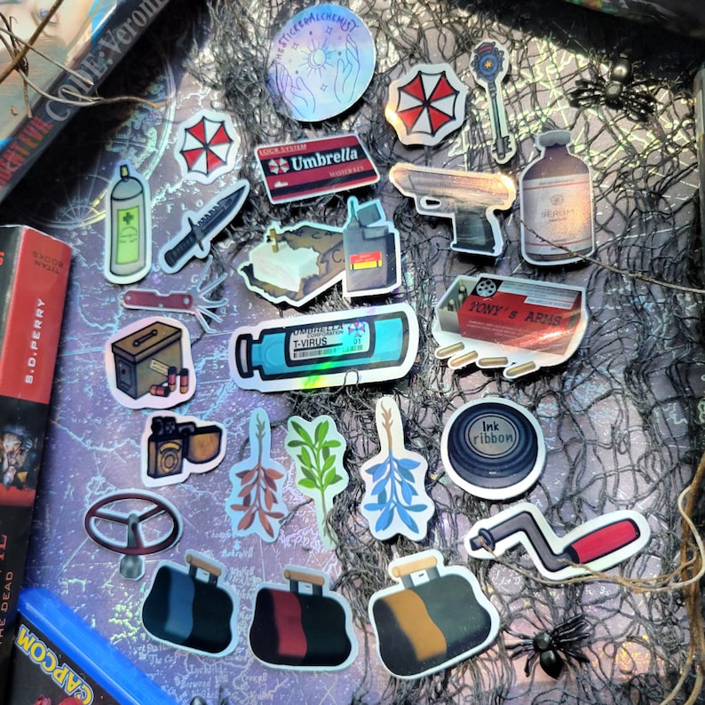 May include: A collection of stickers with various designs, including the Umbrella Corporation logo, a handgun, a vial labeled "T-Virus", and other themed graphics. The stickers are arranged on a purple map background.