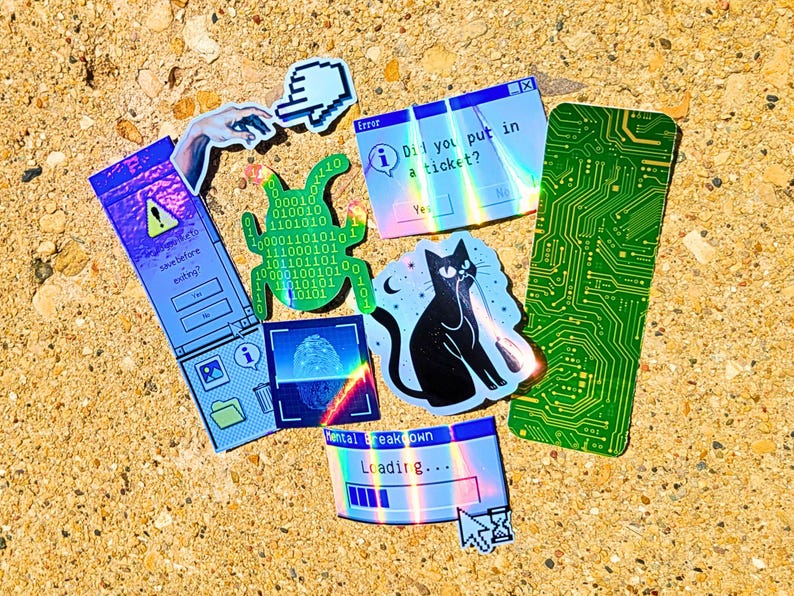 Pode incluir: Uma cole&ccedil;&atilde;o de autocolantes coloridos com um tema tecnol&oacute;gico. Os designs incluem um gato preto com um raio laser, uma placa de circuito e mensagens de erro do computador. Outros autocolantes apresentam c&oacute;digo bin&aacute;rio, uma impress&atilde;o digital e um cursor de m&atilde;o.