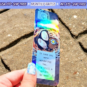 May include: A holographic bookmark featuring a cartoon pug with a text overlay that reads "In case you were wondering: Yes. I'm still a potato. Go away."