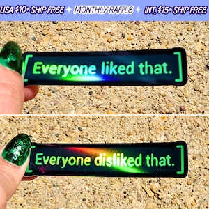 May include: Two black rectangular stickers with the text "Everyone liked that." and "Everyone disliked that." in green and rainbow colors. The stickers have a holographic effect and are held up against a textured background.