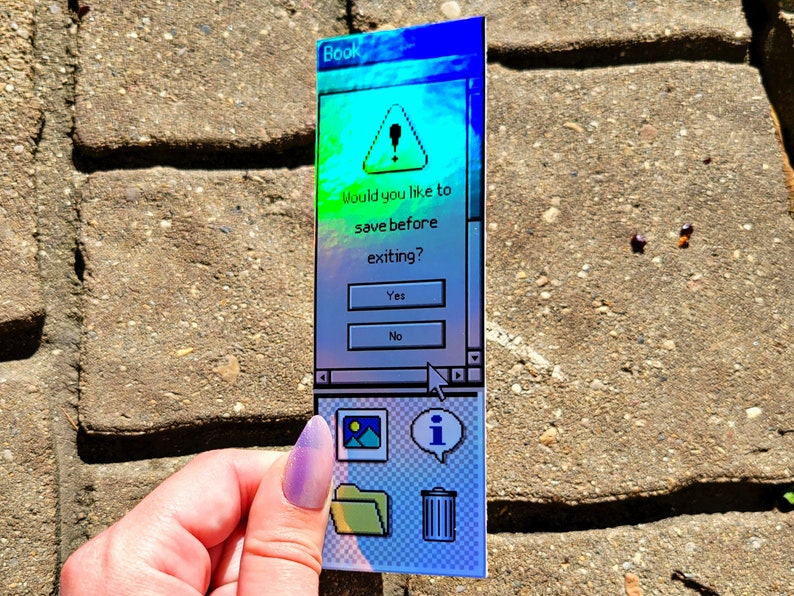 Pode incluir: Um marcador de livros retangular com um design de interface de computador retro. O marcador de livros exibe uma caixa de di&aacute;logo com o texto "Would you like to save before exiting?" e inclui &iacute;cones para uma imagem, uma pasta, informa&ccedil;&otilde;es e uma lixeira.