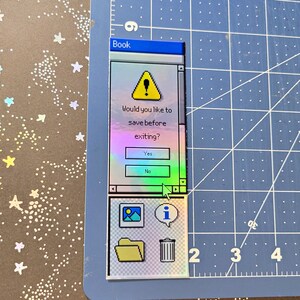 Pode incluir: Um autocolante hologr&aacute;fico em forma de janela de computador retro. O texto diz: "Gostaria de guardar antes de sair?" com os bot&otilde;es "Sim" e "N&atilde;o". O autocolante tamb&eacute;m apresenta &iacute;cones para uma imagem, informa&ccedil;&otilde;es, uma pasta e um caixote do lixo.