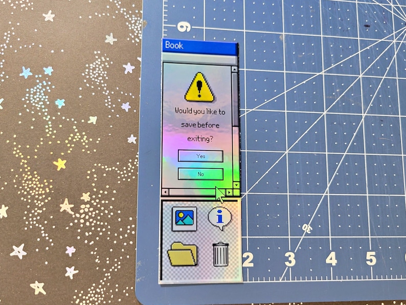 Pode incluir: Um autocolante hologr&aacute;fico em forma de janela de computador retro. O texto diz: "Gostaria de guardar antes de sair?" com os bot&otilde;es "Sim" e "N&atilde;o". O autocolante tamb&eacute;m apresenta &iacute;cones para uma imagem, informa&ccedil;&otilde;es, uma pasta e um caixote do lixo.
