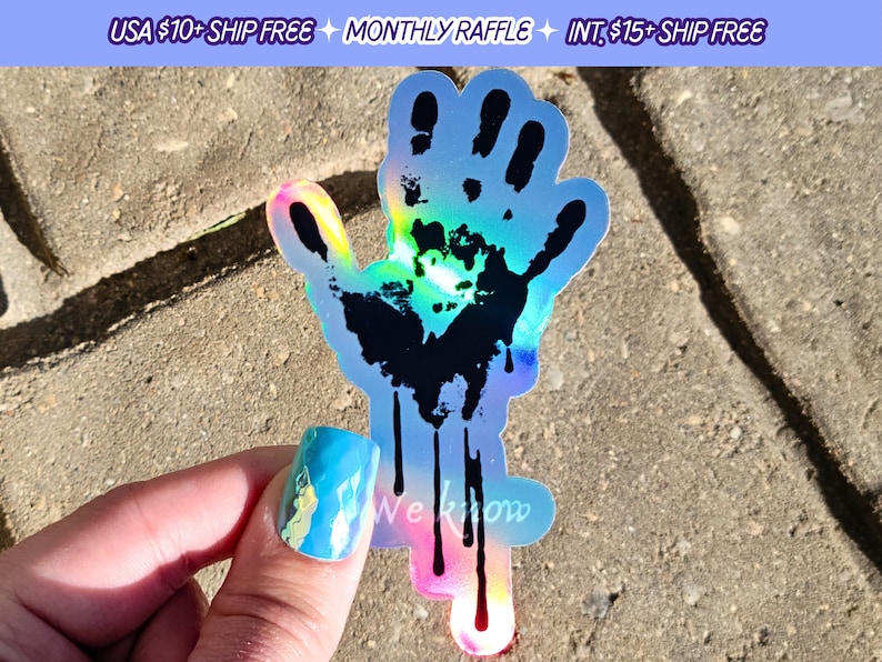 May include: A holographic sticker of a black handprint with dripping black paint. The sticker has a rainbow iridescent finish.