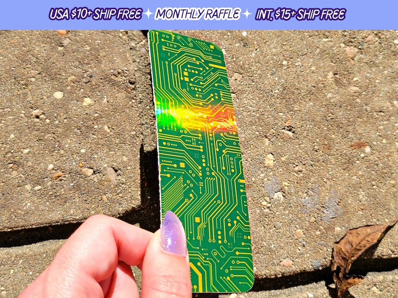 May include: A green and yellow circuit board design bookmark. The bookmark has a rectangular shape with rounded corners. The text "MONTHLY RAFFLE" is visible at the top.
