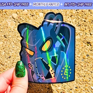 May include: Holographic sticker featuring a stylized robot design with orange eyes and a blue and green color scheme. The sticker has a unique shape and a glossy finish. The sticker has the letter "E" surrounded by stars.