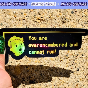 May include: A black and yellow sticker with a holographic finish features a cartoon character with a surprised expression. The text on the sticker reads "You are overencumbered and cannot run!"