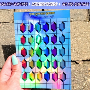 May include: A sheet of 25 iridescent holographic stickers featuring a variety of colored gems in a grid pattern. The sheet is blue with a white grid and the text "THE RUPEES SHEET @THE STICKERALCHEMIST".