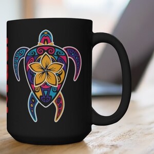May include: Black ceramic coffee mug with a colorful, intricate design of a turtle with a flower in the center. The mug has a white interior and a black handle.