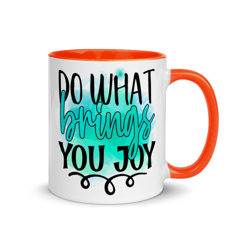 May include: White ceramic coffee mug with an orange rim. The mug features a teal watercolor design with the text "Do what brings you joy" in black lettering.