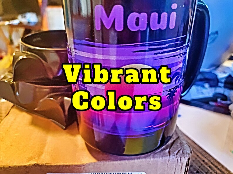 May include: A black ceramic mug with a sunset scene and the word "Maui" in purple lettering. The mug has vibrant colors of pink, purple, and blue. The text "Vibrant Colors" is superimposed on the image.