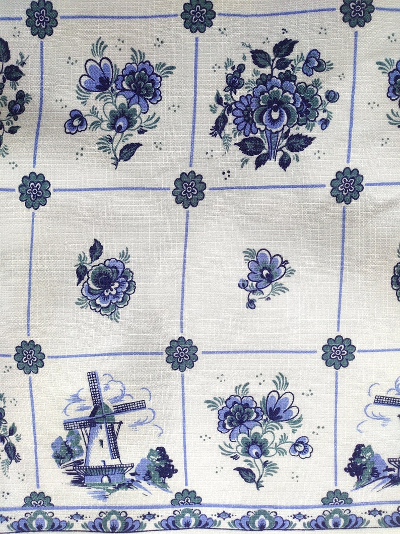 May include: White fabric with a blue and green floral pattern. The fabric features a repeating pattern of flowers and a windmill.