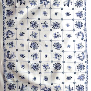 May include: White tablecloth with a blue and white pattern of flowers, windmills, and ships. The pattern is repeated throughout the tablecloth.