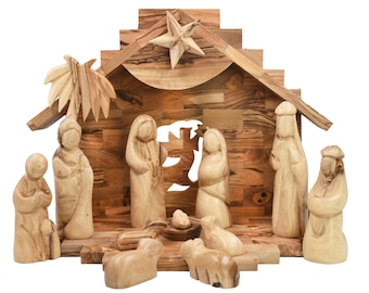 May include: A wooden nativity scene with carved figures, including Mary, Joseph, baby Jesus, and the three wise men. The stable has a star and palm leaves. The figures and stable are made of light brown wood.