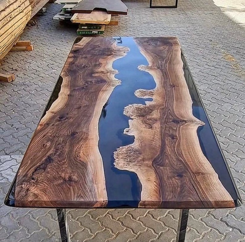 Puede incluir: Una mesa de madera oscura con un r&iacute;o de epoxi negro que atraviesa el centro. La madera tiene un patr&oacute;n de veta natural y el epoxi es liso y brillante.