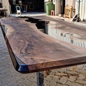 Puede incluir: Una mesa de madera grande con un r&iacute;o de epoxi negro que atraviesa el centro. La mesa tiene un acabado de madera natural y un borde negro.