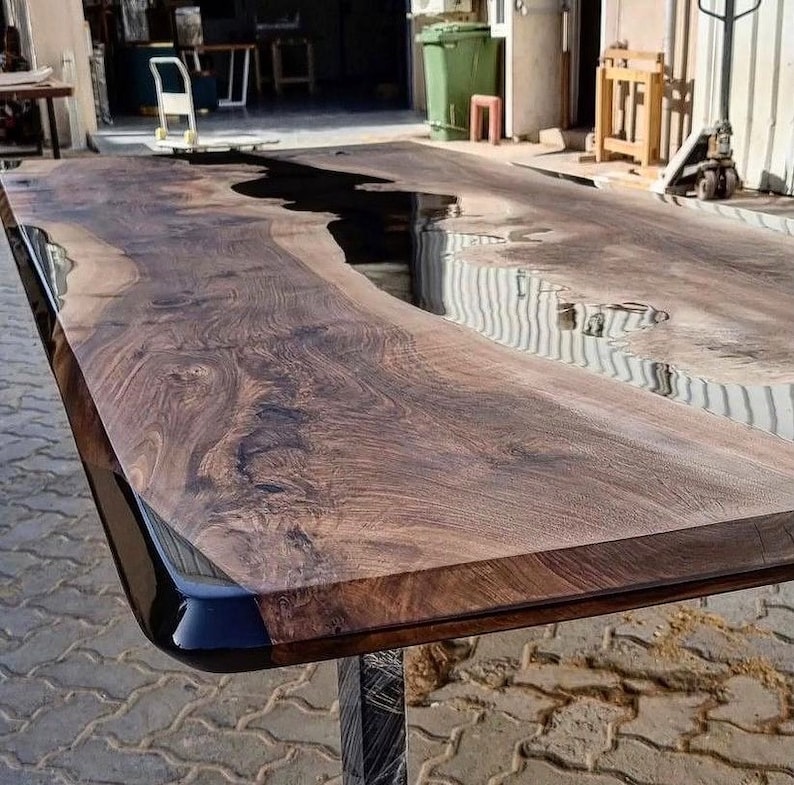 Puede incluir: Una mesa de madera grande con un r&iacute;o de epoxi negro que atraviesa el centro. La mesa tiene un acabado de madera natural y un borde negro.