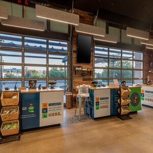 May include: A blue and green checkout counter with a sign that reads "Healthy, Fresh & Affordable meals made for YOU." The counter has a wicker basket with produce and a sign that reads "A new lifestyle. You have been waiting for it. HERE."