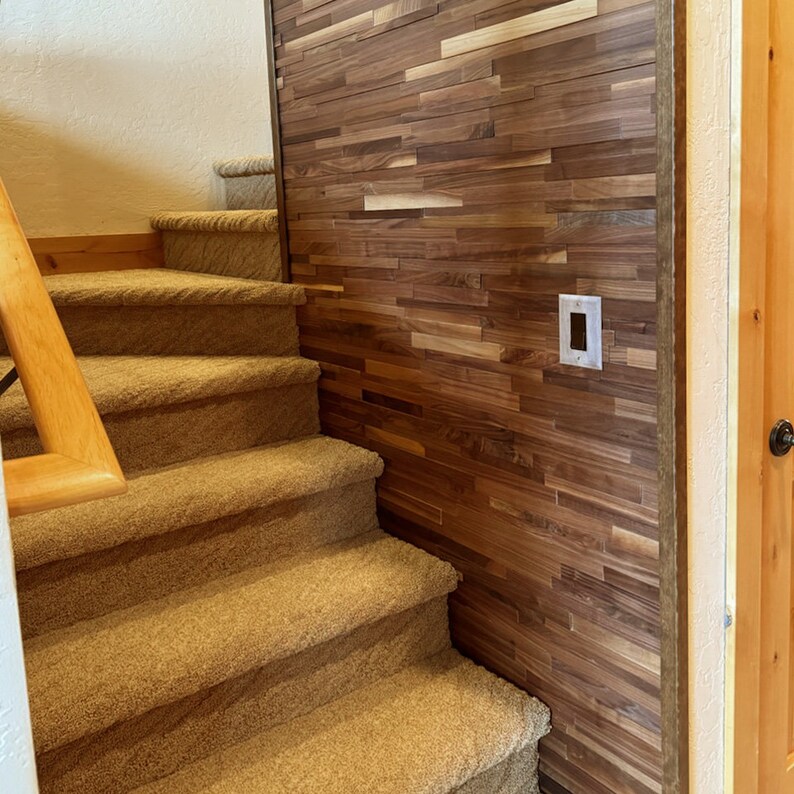 Pu&ograve; includere: Scale rivestite in moquette che conducono a un pianerotto con una parete rivestita in pannelli di legno scuro. Un interruttore della luce &egrave; visibile sulla parete.