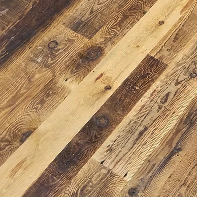 May include: Close-up of a wood floor with a diagonal pattern of light and dark brown wood planks. The wood has a rustic, reclaimed look with knots and grain patterns.