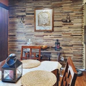 May include: A dining room table setting with a white tablecloth, two placemats, and a woven placemat. The table is set with two chairs, one with a woven back and the other with a wooden back. The wall behind the table is covered in wood paneling.