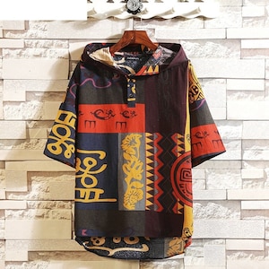 以下が含まれることがあります： カラフルな幾何学模様のショートスリーブフード付きシャツ。シャツは首元にボタン留めがあり、軽量な生地で作られています。