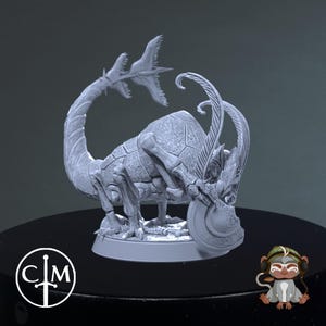 May include: A grey, 3D-printed fantasy creature figurine with a segmented body, curved tail, and elaborate head ornamentation. The figurine is on a round base, with a logo in a circle on the base. A cartoon monkey is in the lower right corner.