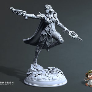 May include: A grey, detailed miniature figurine of a female warrior in a dynamic pose, holding a crossbow in one hand and a sword in the other. She is wearing armour with intricate designs and a flowing cape. The figurine is set on a rocky base.