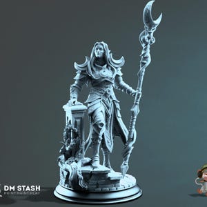 May include: A light gray resin miniature figurine of a warrior standing on a stone base, wearing ornate armor and holding a tall staff topped with a crescent moon symbol. The base features a pillar and decorative carvings. Text reads DM STASH.