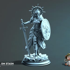 Op de afbeelding: Een gedetailleerd, grijs beeldje van een krijger in harnas, met een zwaard en schild. De figuur heeft een halo en staat op een rotsachtige basis. Het schild heeft een gedetailleerd embleem. De basis heeft een cirkelvorm.