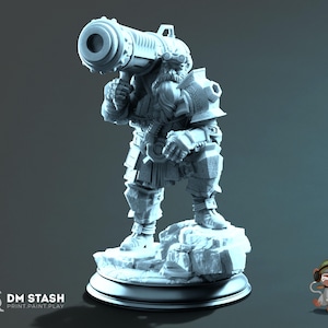 Op de afbeelding: Een lichtgrijs miniatuurfiguur van een bebaarde dwergkrijger die op een rotsachtige basis staat. Het figuur draagt zware bepantsering en een bril en houdt een groot cilindrisch kanon over de rechterschouder. De tekst DM STASH PRINT PAINT PLAY is zichtbaar.