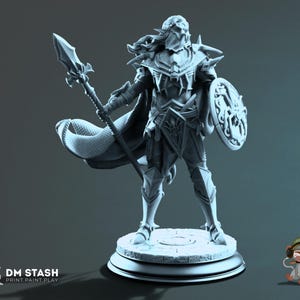 Könnte beinhalten: Eine graue Miniaturfigur aus Harz, die einen Krieger auf einem runden Steinsockel darstellt. Die Figur trägt eine verzierte Plattenrüstung, einen wehenden Umhang und hält einen langen Speer sowie einen runden Schild mit Spinnenemblem. DM STASH PRINT.PAINT.PLAY.