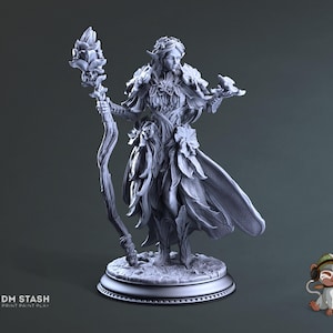 Peut inclure: Une figurine miniature grise et détaillée d'une femme elfe aux cheveux longs et portant une robe fluide faite de feuilles et de fleurs. Elle tient un bâton surmonté d'une fleur et un petit oiseau dans l'autre main. La figurine est debout sur une base ronde.