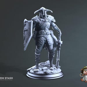Könnte beinhalten: Eine graue, detaillierte Miniaturfigur eines Kriegers, der eine Rüstung trägt und ein Schwert und einen Schild hält. Die Figur steht auf einem runden Sockel.
