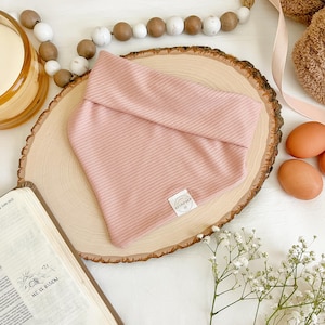 May include: A pink ribbed fabric bandana on a wooden slice with a small white circle label that says "Tiny Shop".