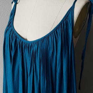 Blue turquoise open back maxi dress with tie shoulders and a flowy oversized fit on the beach.
