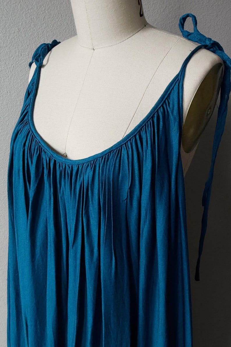 Blue turquoise open back maxi dress with tie shoulders and a flowy oversized fit on the beach.