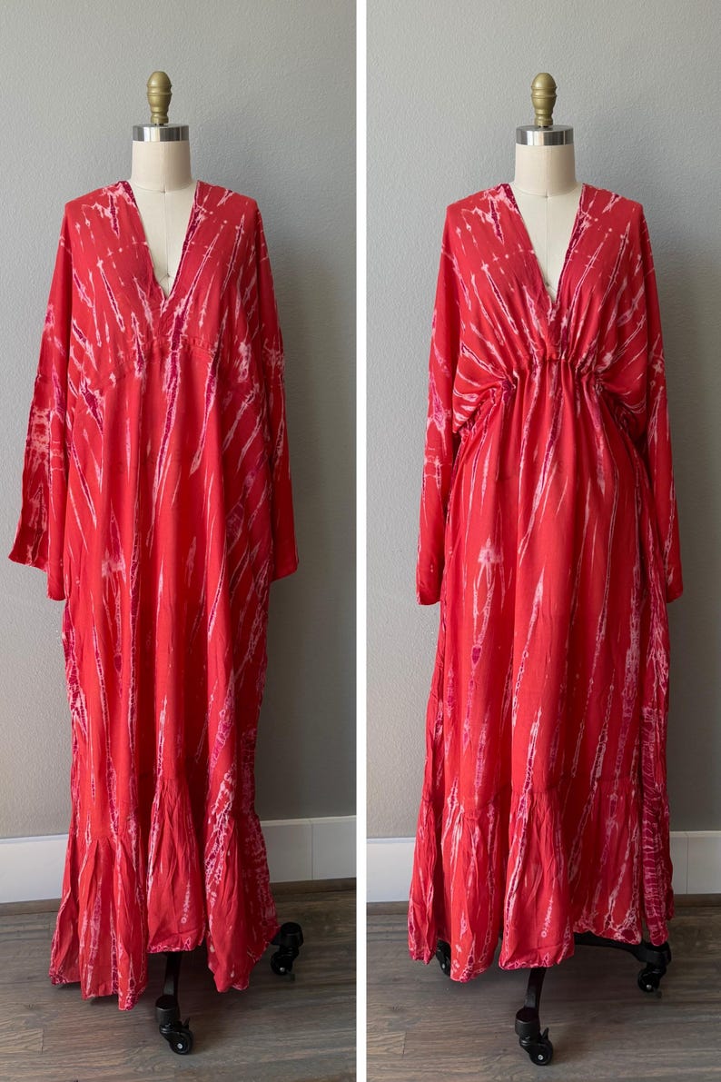 A red maxi dress with a V-neckline and long sleeves. The dress has a cinched waist and a flowing skirt.