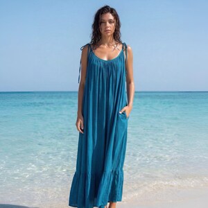 Blue turquoise open back maxi dress with tie shoulders and a flowy oversized fit on the beach.