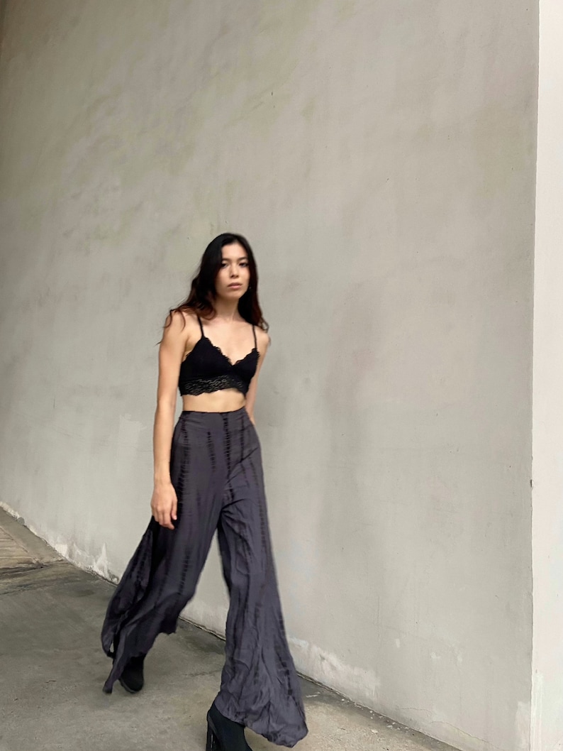 Puede incluir: Una mujer con un bralette de encaje negro y pantalones anchos de color gris oscuro con un patr&oacute;n de tie-dye.
