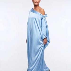 Flowy blue kaftan maxi dress with off shoulder neckline and self-tie bow, shown as a loose handmade vacation dress for women.
