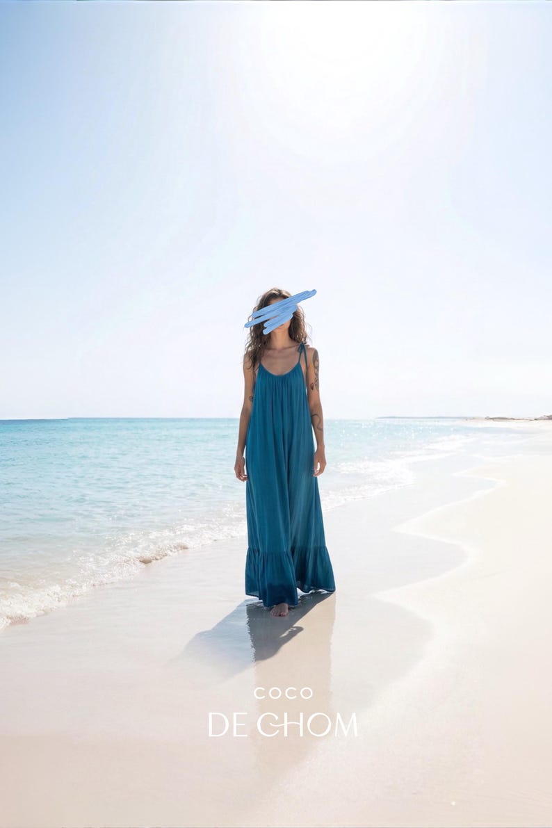 Blue turquoise open back maxi dress with tie shoulders and a flowy oversized fit on the beach.